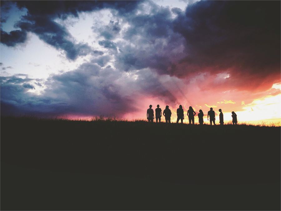 A group gathered on a hillside at sunset